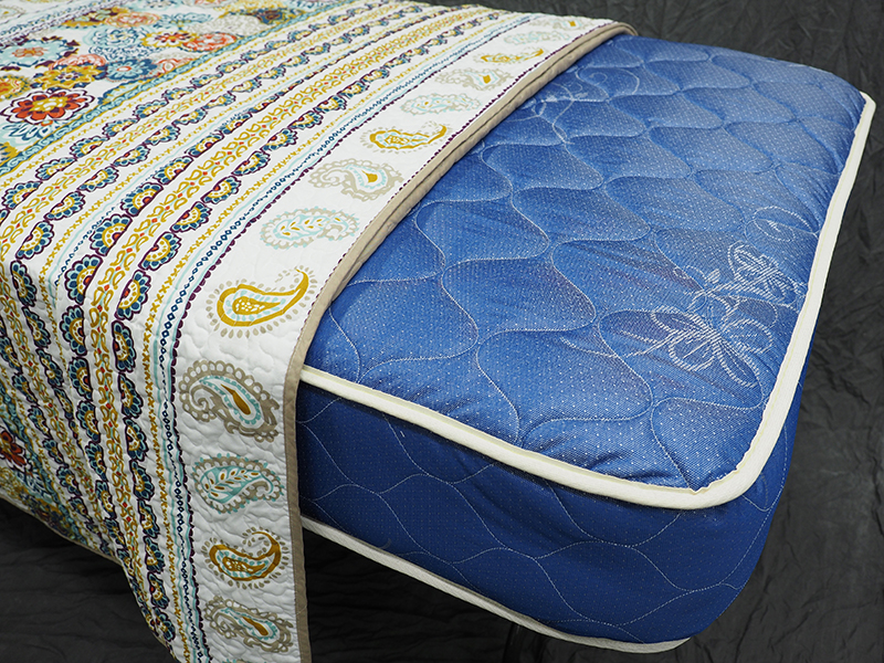 a blue mattress half covered with a quilt